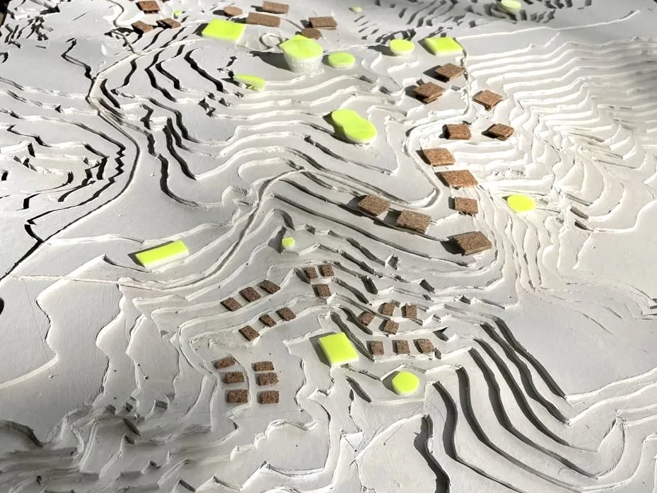 Una maqueta blanca del terreno con piezas de corcho y lima que marcan qué va en cada ladera